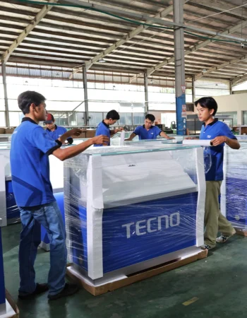 Production team packing retail display units using plastic wrapping in a manufacturing facility in Indonesia